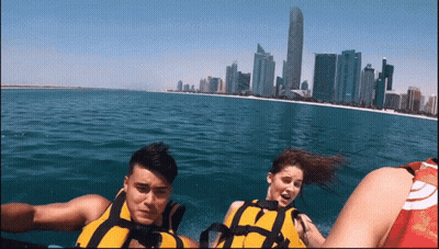 A Man And A Woman Are Riding A Boat In The Ocean GIF