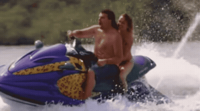 A Man And A Woman Are Riding A Jet Ski On The Water . GIF