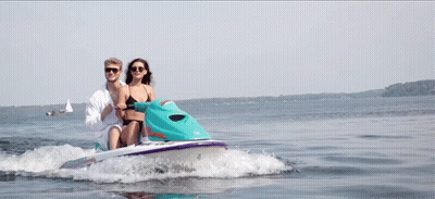A Man And A Woman Are Riding A Jet Ski With A License Plate That Says Jm 4666 GIF