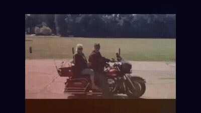 A Man And A Woman Are Riding A Motorcycle With A Dog On The Back . GIF