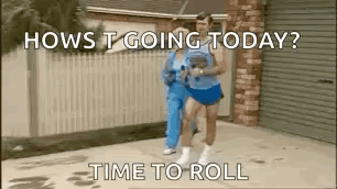 A Man And A Woman Are Running Down A Sidewalk In Front Of A Garage . GIF