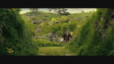 A Man And A Woman Are Running Through A Lush Green Field GIF