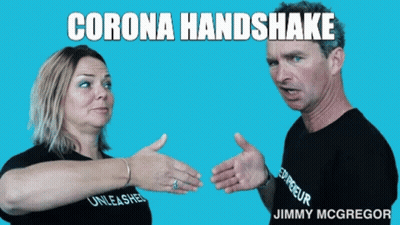 A Man And A Woman Are Shaking Hands With The Words Corona Handshake Above Them GIF