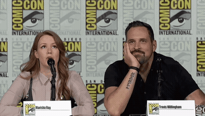 A Man And A Woman Are Sitting At A Comic Con Panel GIF
