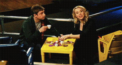 A Man And A Woman Are Sitting At A Small Table GIF