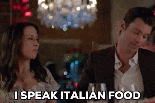 A Man And A Woman Are Sitting At A Table And The Woman Is Saying I Speak Italian Food GIF