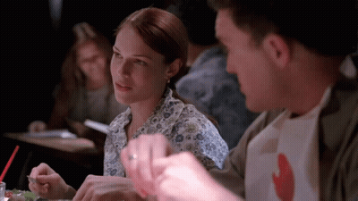 A Man And A Woman Are Sitting At A Table Eating Food GIF