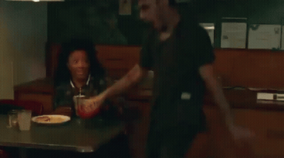 A Man And A Woman Are Sitting At A Table In A Diner Eating Food . GIF