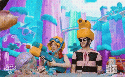 A Man And A Woman Are Sitting At A Table In Front Of A Colorful Background . GIF
