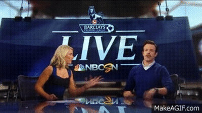 A Man And A Woman Are Sitting At A Table In Front Of A Sign That Says Live GIF