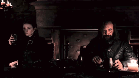 A Man And A Woman Are Sitting At A Table In The Dark GIF
