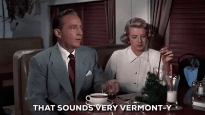 A Man And A Woman Are Sitting At A Table With A Cup Of Coffee And The Words That Sounds Very Vermont-Y GIF