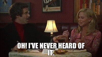 A Man And A Woman Are Sitting At A Table With A Lamp . GIF
