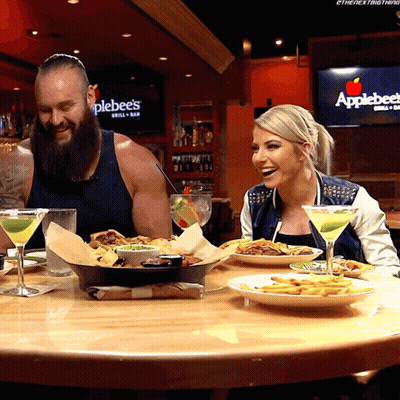 A Man And A Woman Are Sitting At A Table With Plates Of Food In Front Of An Applebee 'S Sign GIF