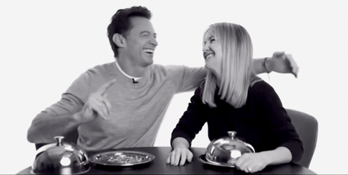 A Man And A Woman Are Sitting At A Table With Plates Of Food On It GIF