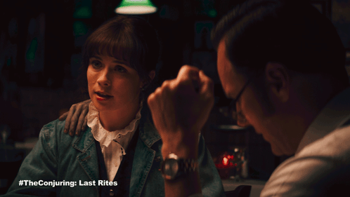 A Man And A Woman Are Sitting At A Table With The Conjuring Last Rites Written On The Bottom GIF