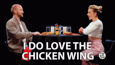 A Man And A Woman Are Sitting At A Table With The Words I Do Love The Chicken Wing On The Bottom GIF
