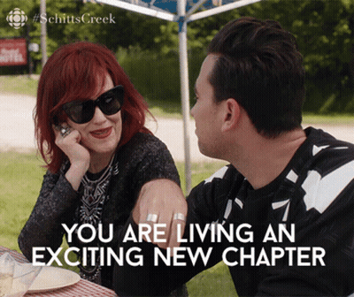 A Man And A Woman Are Sitting At A Table With The Words " You Are Living An Exciting New Chapter " GIF