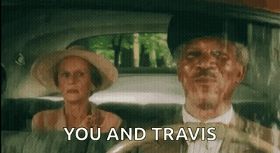 A Man And A Woman Are Sitting In A Car And The Man Is Driving . GIF