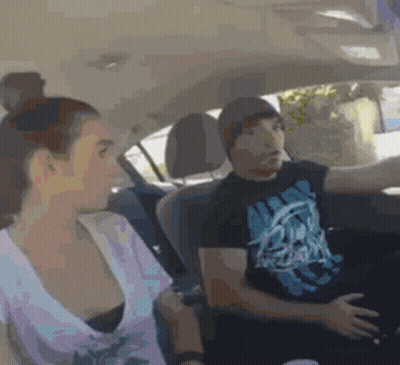 A Man And A Woman Are Sitting In A Car And The Man Is Wearing A T-Shirt With A Skull On It GIF