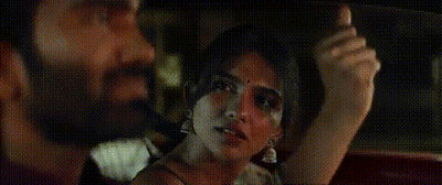 A Man And A Woman Are Sitting In A Car At Night . The Woman Is Wearing Earrings And A Necklace . GIF