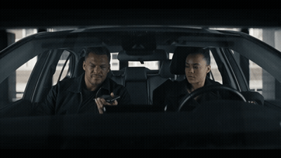 A Man And A Woman Are Sitting In A Car Looking At Something GIF