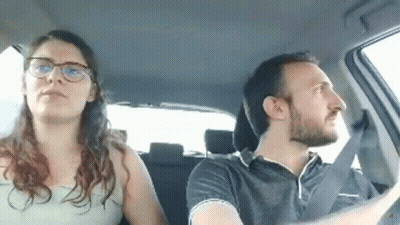 A Man And A Woman Are Sitting In A Car . The Man Is Driving And The Woman Is Sitting In The Back Seat . GIF