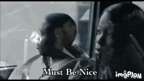 A Man And A Woman Are Sitting In A Car With The Words Must Be Nice On The Bottom GIF