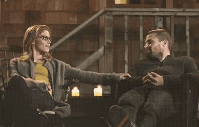 A Man And A Woman Are Sitting In A Chair Holding Hands . GIF