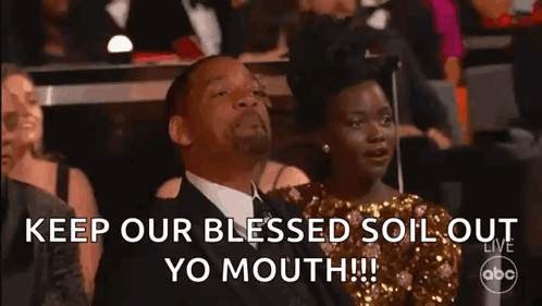 A Man And A Woman Are Sitting In A Crowd At A Awards Show And The Man Is Making A Funny Face . GIF