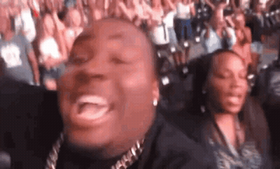 A Man And A Woman Are Sitting In A Crowd Of People . GIF