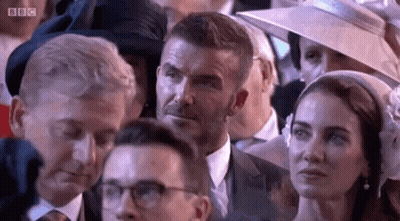 A Man And A Woman Are Sitting In A Crowd Of People . GIF