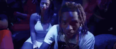 A Man And A Woman Are Sitting In A Dark Room With A Blue Light Behind Them . GIF