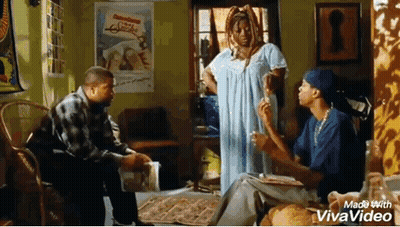 A Man And A Woman Are Sitting In A Living Room Talking To Each Other . The Woman Is Smoking A Cigarette . GIF
