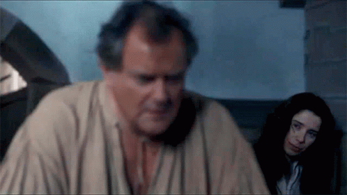 A Man And A Woman Are Sitting In A Room And The Man Is Looking At The Woman GIF