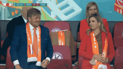 A Man And A Woman Are Sitting In A Stadium Watching A Game . GIF