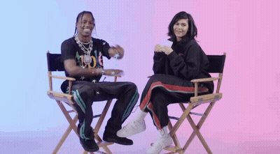 A Man And A Woman Are Sitting In Directors Chairs And Smiling GIF