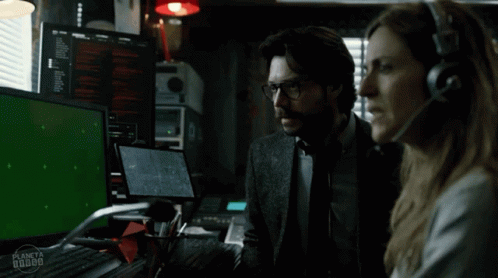 A Man And A Woman Are Sitting In Front Of A Green Screen GIF