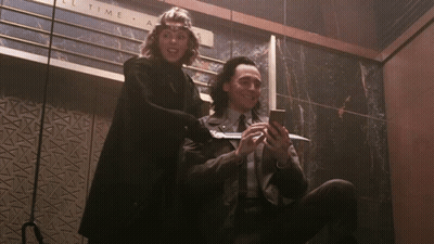 A Man And A Woman Are Sitting In Front Of A Sign That Says " All Time " GIF