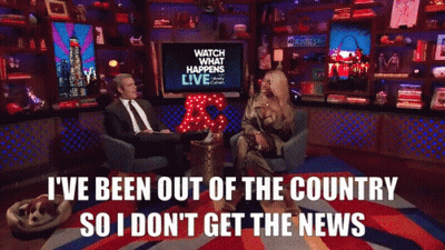 A Man And A Woman Are Sitting In Front Of A Tv That Says Watch What Happens Live GIF