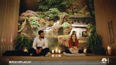 A Man And A Woman Are Sitting In Front Of A Wall With A Waterfall In The Background GIF