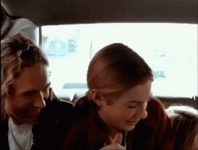 A Man And A Woman Are Sitting In The Back Of A Car . GIF