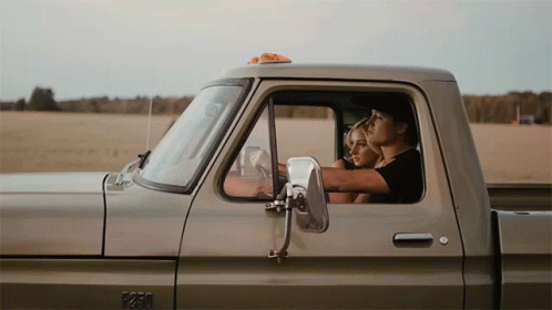 A Man And A Woman Are Sitting In The Back Of A Pickup Truck With The Number 1250 On The Side GIF