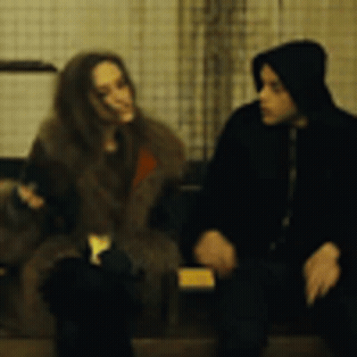 A Man And A Woman Are Sitting Next To Each Other And Talking . GIF