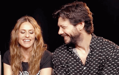 A Man And A Woman Are Sitting Next To Each Other And The Woman Is Wearing A Shirt That Says Xa GIF