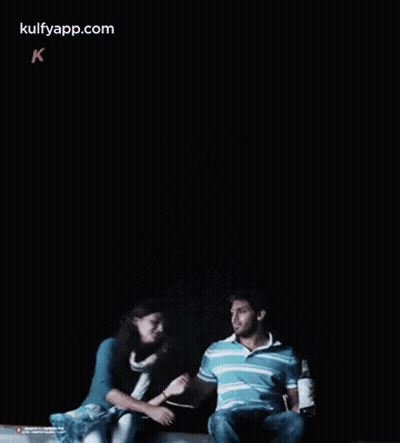 A Man And A Woman Are Sitting Next To Each Other In A Dark Room .. GIF
