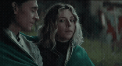 A Man And A Woman Are Sitting Next To Each Other In A Field . GIF