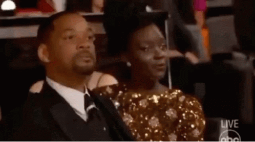 A Man And A Woman Are Sitting Next To Each Other In A Theatre . GIF