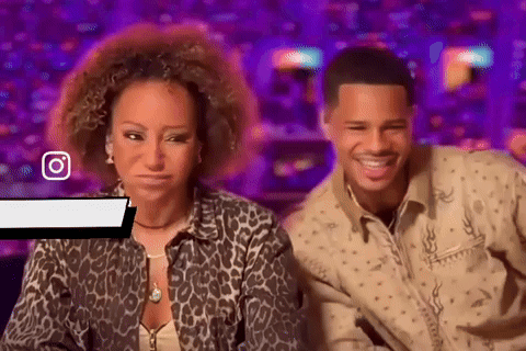 A Man And A Woman Are Sitting Next To Each Other In Front Of A Purple Background . GIF