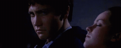 A Man And A Woman Are Sitting Next To Each Other In The Dark . GIF
